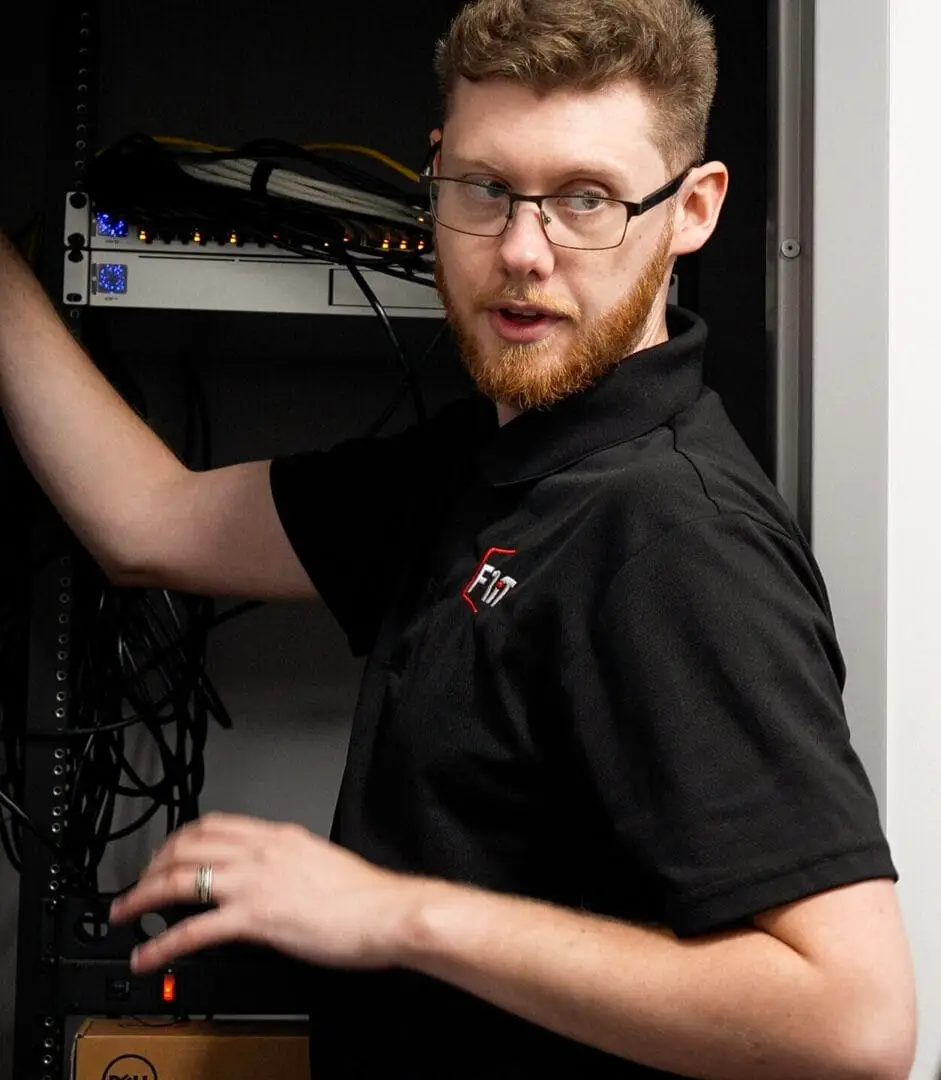 F1 iT technician connecting network cables in a dental practice server rack